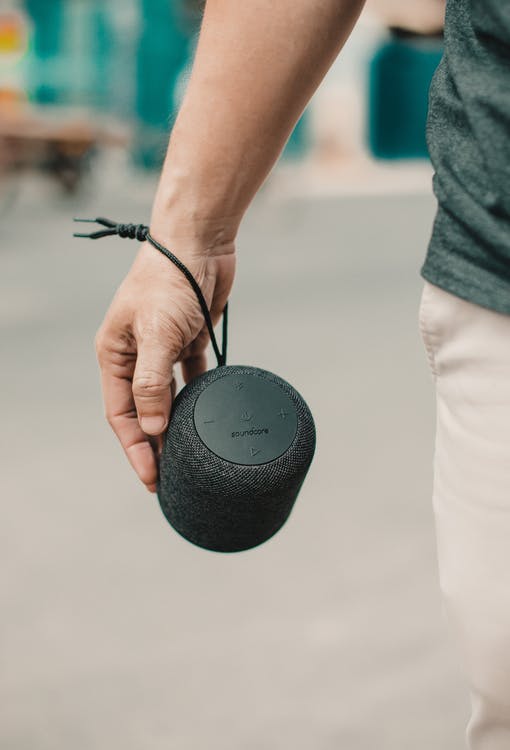  A Faceless Person with a Black Portable Speaker Tied Around Their Wrist